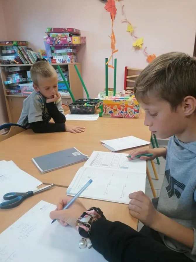 Na zdjęciu dzieci odrabiający zadania szkolne
