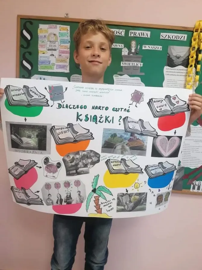 Na zdjęciu podopieczny świetlicy trzymający w rękach efekt swojej pracy, czyli prezentację "Dlaczego warto czytać książki?"