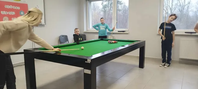 Na zdjęciu opiekun świetlicy wraz z dziećmi w trakcie gry w bilarda (spotkanie z okazji tłustego czwartku)