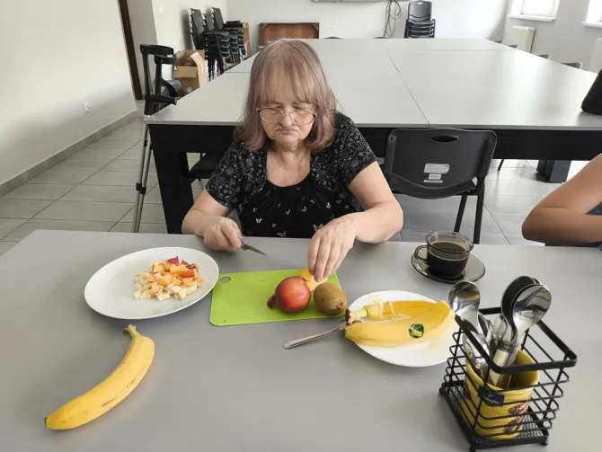 Na zdjęciu uczestniczka spotkania podczas przygotowywania sałatki owocowej