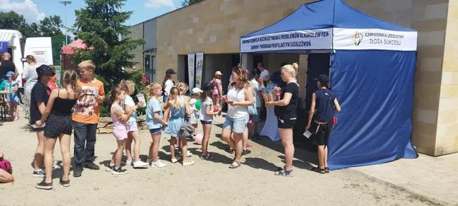 Na zdjęciu uczestnicy akcji "Bezpieczni w wakacje" stojący w kolejce do stoiska Gminnej Komisji Rozwiązywania Problemów Alkoholowych w Czerwionce-Leszczynach