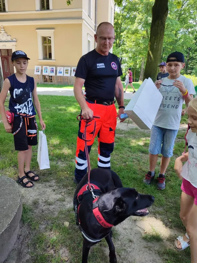 Na zdjęciu ratownik z Grupy Poszukiwawczo-Ratowniczej Knurów z psem ratownikiem, Zoya, wraz z uczestnikami akcji "Bezpieczni w wakacje"