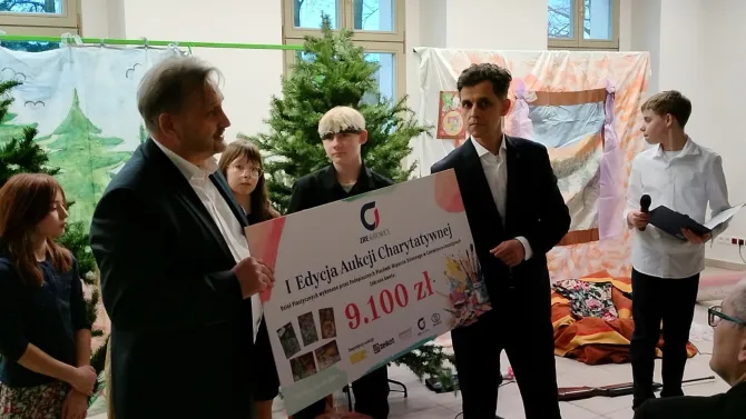 Na zdjęciu przedstawiciele firmy ZRE Katowice S.A. trzymający symboliczny czek na kwotę 9 100,00 zł. W tle podopieczni Placówki Wsparcia Dziennego w Czerwionce-Leszczynach