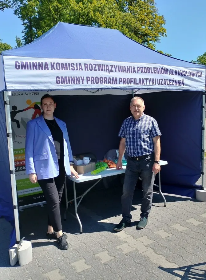 Na zdjęciu stoisko Gminnej Komisji Rozwiązywania Problemów Alkoholowych w Czerwionce-Leszczynach, przy którym stoją członek Komisji oraz Koordynator kampanii profilaktycznych na terenie Gminy i Miasta Czerwionka-Leszczyny